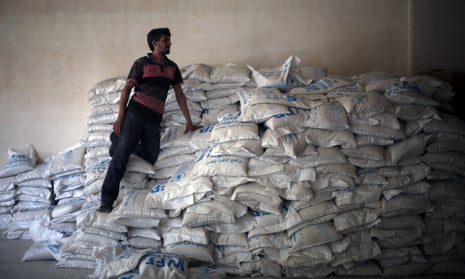 A Syrian man stands on aid parcels from the UN World Food Programm (WFP) and the Syrian Arab Red Crescent in Saqba, Syria. 