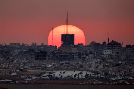 The sun sets behind destroyed buildings in the Gaza Strip