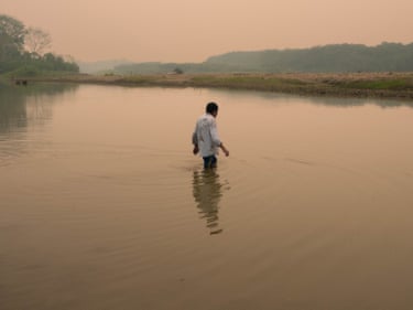Luis Díaz, In The Song of Invisible Birds by Luis Díaz Crossing the Alto Madre de Dios River under a red sky caused by fires in the southern Amazon. Luis works for the Ministry of Culture as a protection agent for the Mashco-Piro, serving as one of the few intermediaries who communicates directly with them. Although some encounters occur with their consent, Luis has witnessed how clearly they express that they want nothing to do with the Western world—a world they see as one that only destroys. (Florence Goupil / Belfast Photo Festival)