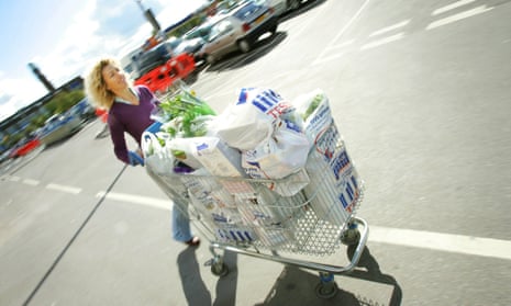 A woman pushes a Tesco trolley full of shopping