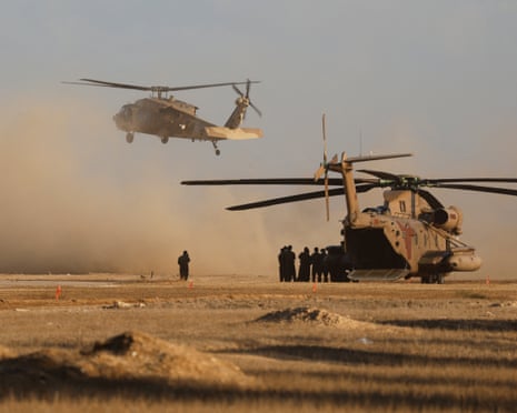 Members of Israeli forces stand next to a helicopter in Reim