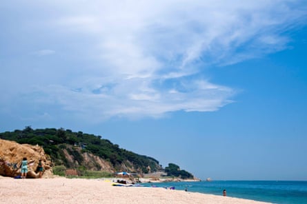 white sand beach, blue sea and rocky headland under a blue sky