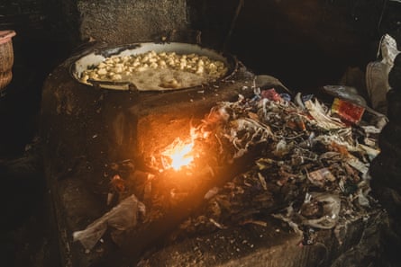 Plastic scraps being loaded into an open furnace used to fry tofu at a factory in Tropodo, Indonesia