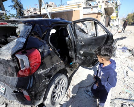A boy peering in to a badly damaged car