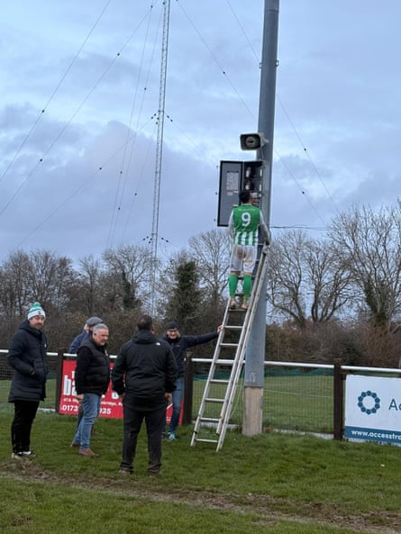 Rusthall striker Charlie Clover, an electrician by day, tries to fix the floodlights during a match.