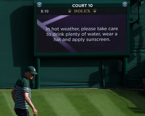A ground staff member walks past a screen with heatwave advisory ahead of the tournament at Wimbledon, London.