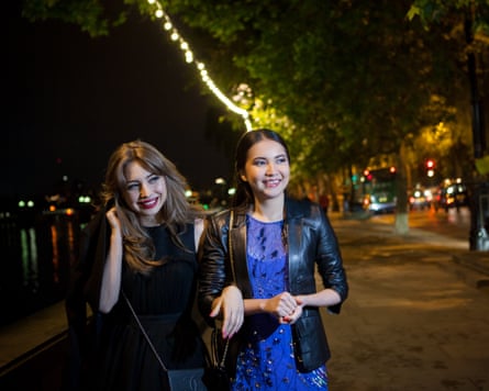 Two female friends strolling along riverside at night