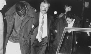 Yusef Salaam, left, is led away by a detective after being arrested in Central Park for allegedly attacking Trisha Meili.