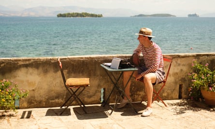 Josh O'Connoll as Larry in the Durrells, sitting at desk with typewriter, overlooking sea