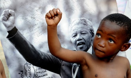 A young member of the Maitibolo Cultural Troupe poses on July 14, 2013 in front of a photograph of former South African President Nelson Mandela in Pretoria. Graca Machel, the widow of Mandela, said the whole continent was in danger of neglecting its youth