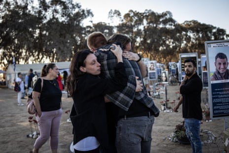 People embrace next to memorials of victims of the 2023 October 7 attacks at the Nova festival grounds in southern Israel.