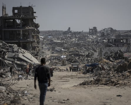 People walk through vast areas of rubble.