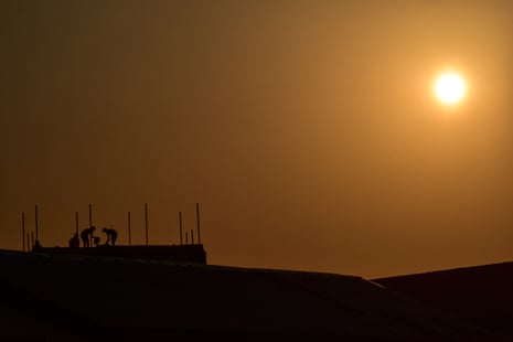 Labourers work on top of a building as the sun sets during a heatwave in Srinagar.