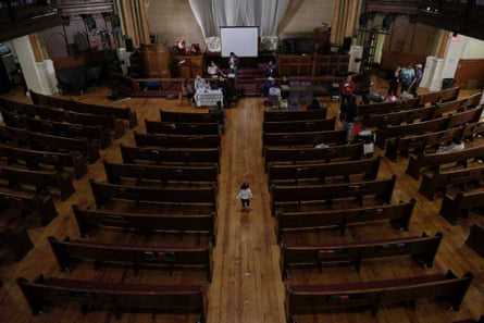 A church with a young girl walking down the aisle with people gathered in the front pews.