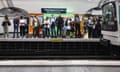 Commuters line a platform as a metro train arrives