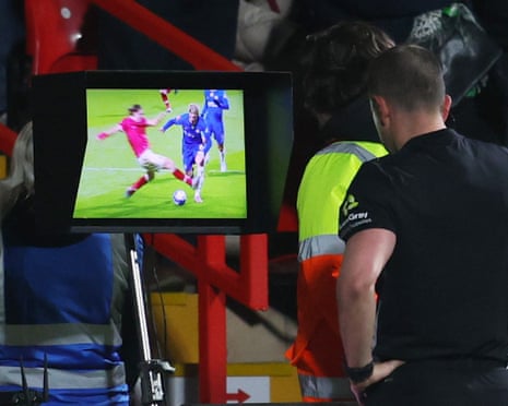 Referee Peter Bankes looks at the VAR monitor before showing Wrexham’s George Dobson a red card after he fouled Chelsea’s Alejandro Garnacho.