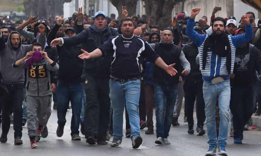 Tunisian protesters gesture towards security forces during clashes in the town of Tebourba.