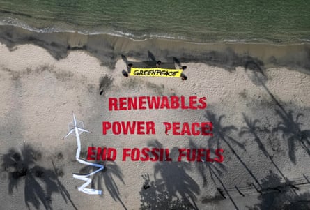 Aerial view of Greenpeace members next to a sign in the sand reading “Renewables Power Peace! End Fossil Fuels”