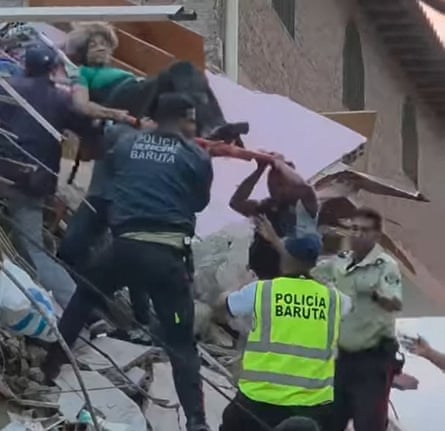 Emergency workers carry a person on a stretcher over a pile of rubble