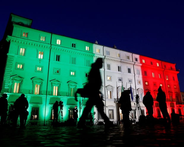Palazzo Chigi lit up in the Italian flag colours with silhouettes of people in front