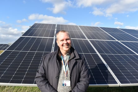 Dale Hoyland smiling in front of a bank of solar panels