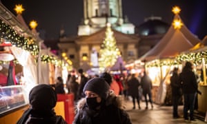 People wearing protective face masks walk at a Christmas market at Gendarmenmarkt square, in Berlin, Germany.
