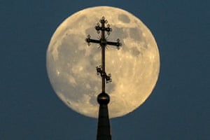 The moon appears behind a cross on top of an Orthodox church in the city of Rossosh, Voronezh region, Russia