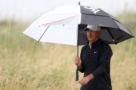 Brooks Koepka holds an umbrella