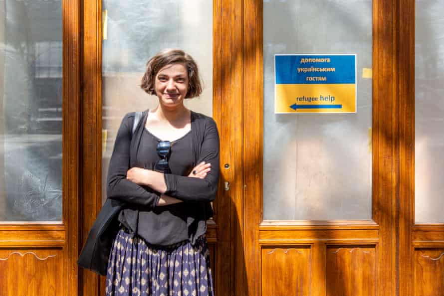 A young female volunteer smiles at the camera. Next to her is a sign saying