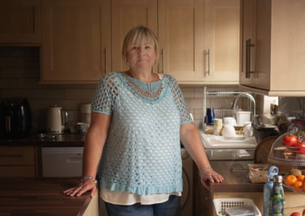 Andrea Tucker stands in her kitchen in a teal crocheted top, resting her hands on counters