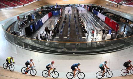 Members of the French national cycling team train while people wait to be vaccinated inside the national Velodrome in Saint-Quentin-en-Yvelines, near Paris.
