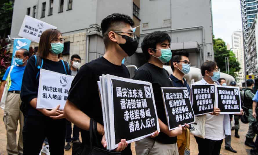 Pro-democracy protesters hold placards as they march in Hong Kong on 22 May.