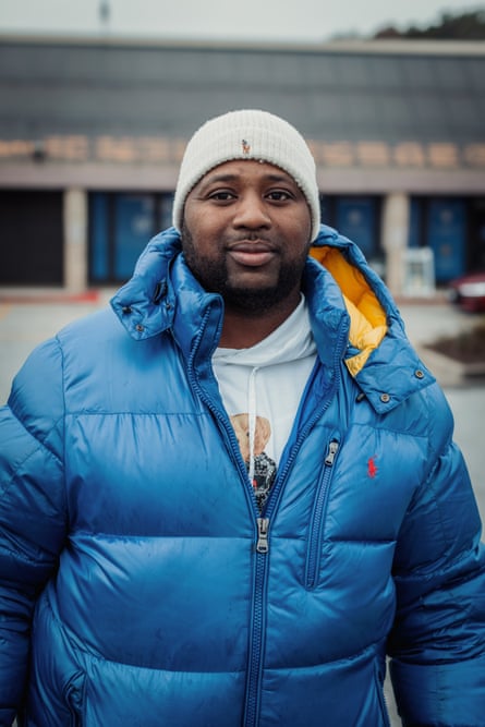 man in blue jacket smiles in parking lot outside