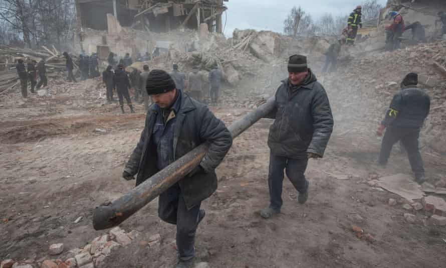 People remove debris at the site of a military base building that, according to the Ukrainian ground forces, was destroyed by an air strike, in the Sumy region.