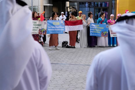 Emirati men watch a demonstration by vegans outside the conference on Thursday morning.