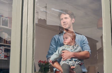 Richard Godwin and his baby, Aubrey, seen though the window of their home