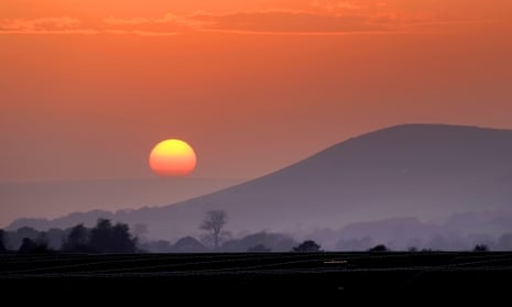 The sun setting behind Mount Caburn, near Lewes, in the South Downs.