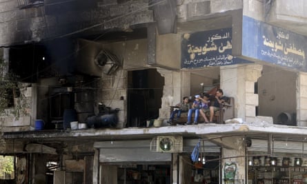 Residents sit on a sofa on a balcony of a damaged building in Aleppo’s al-Shaar neighbourhood in Syria.