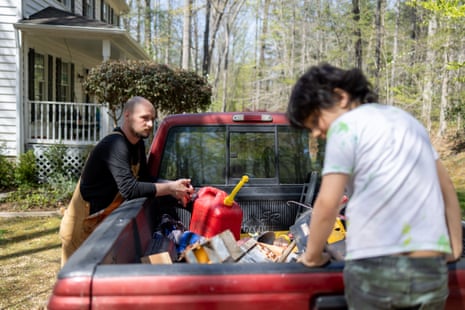 A man looks at his son standing on a car trunk