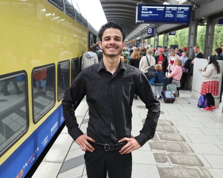 a man poses for a photo next to a train