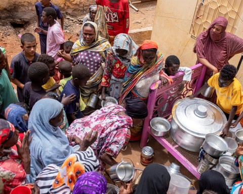 Women in colourful clothing queue for food