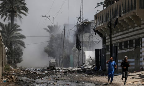 Palestinians run for cover after an Israeli air strike on Khadija school leaves wreckage on the ground and the air filled with smoke