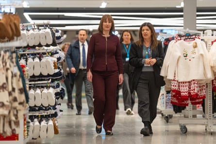 Rachel Reeves (burgundy suit), speaks with staff as they walkbetween display rails as she visits a Primark store in London