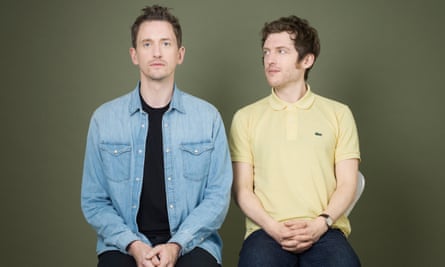 John Robins, wearing a blue denim shirt and Elis James, in a yellow polo shirt, sitting side by side