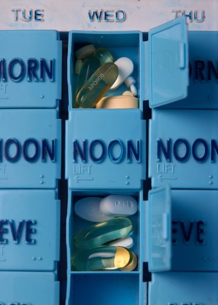 A blue, daily medicine box with doses of medications and different pills