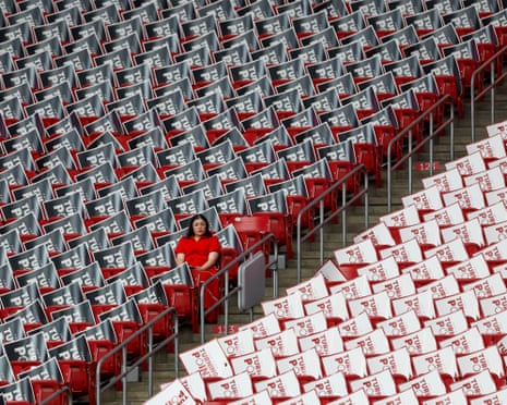 woman wearing red sits inside otherwise empty stadium