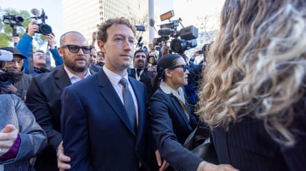 Mark Zuckerberg in a suit surrounded by cameras and people