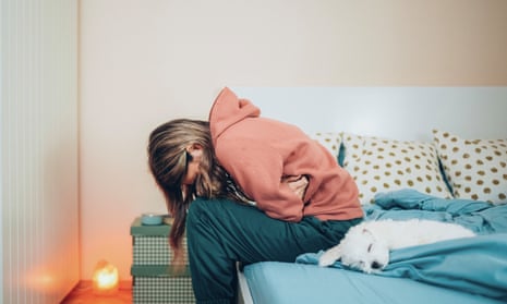 Woman with stomach pain resting on bed with her dog