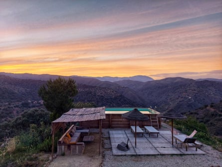 An outdoor pool on high ground at sunrise surrounded by mountains
