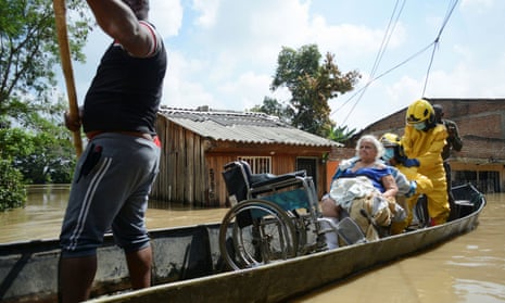 Rescue workers help evacuate a woman in a wheelchair in a canoe at after the Cauca River overflowed due to heavy rains, in Cali, Colombia, November 2022.